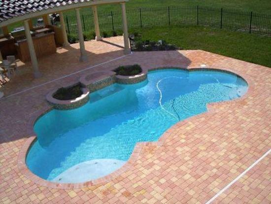 Example of a small transitional backyard concrete paver and custom-shaped hot tub design in Tampa