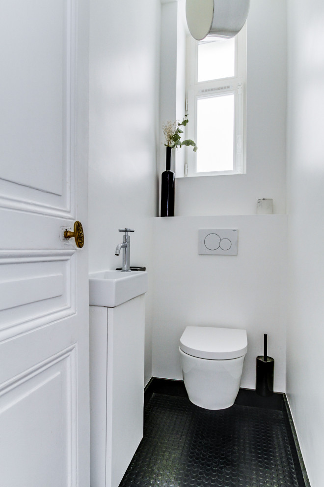 Esempio di un bagno di servizio moderno di medie dimensioni con WC sospeso, pareti bianche, pavimento in linoleum, lavabo da incasso e pavimento nero