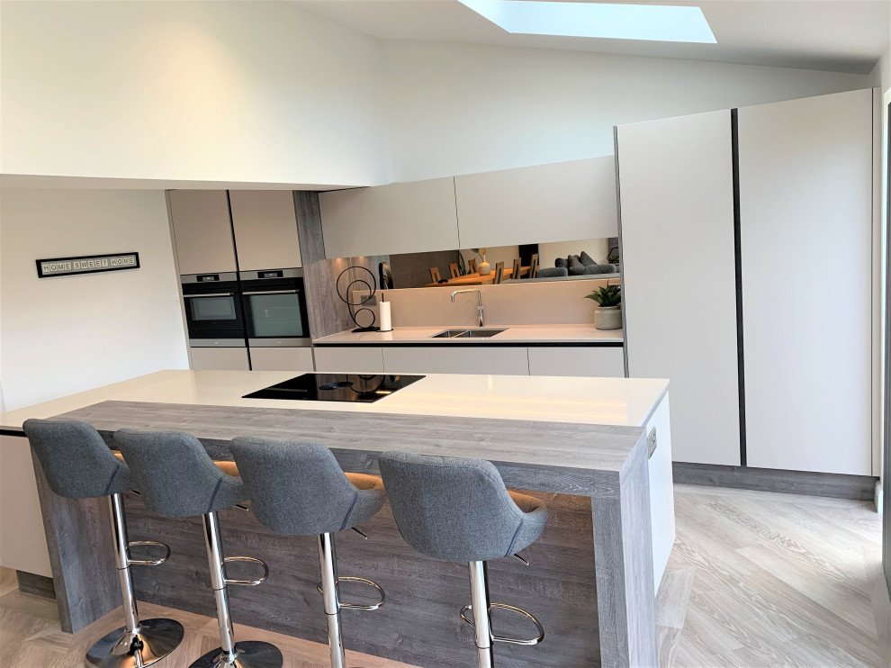 Inspiration for a large contemporary single-wall open plan kitchen in Other with a single-bowl sink, flat-panel cabinets, medium wood cabinets, quartz worktops, glass sheet splashback, black appliances, vinyl flooring, an island and beige worktops.