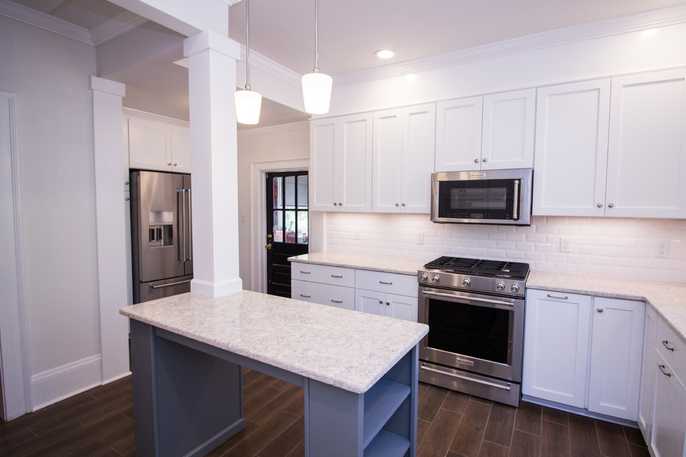 Eat-in kitchen - small u-shaped ceramic tile eat-in kitchen idea with an undermount sink, shaker cabinets, white cabinets, quartz countertops, white backsplash, subway tile backsplash, stainless steel appliances, an island and white countertops