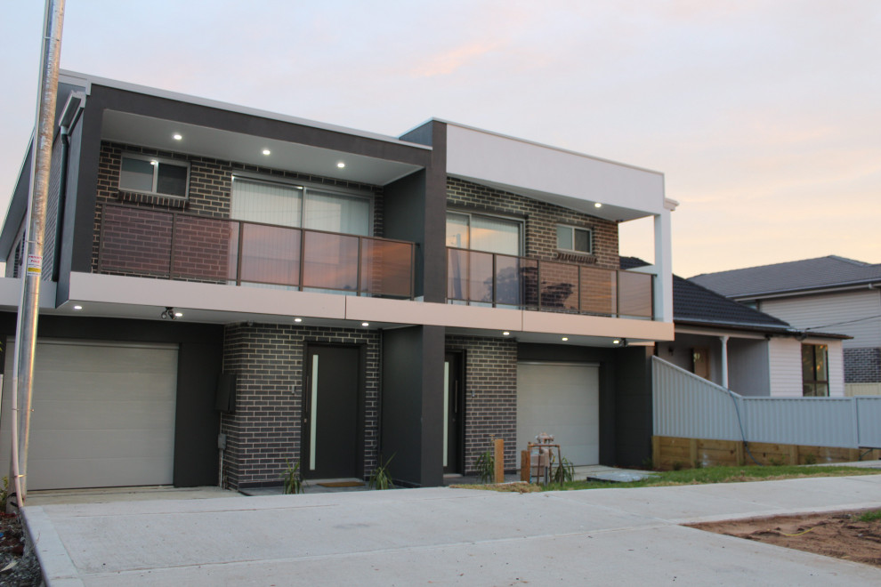 Immagine della facciata di una casa bifamiliare beige con rivestimento in mattoni, tetto piano, copertura in metallo o lamiera, tetto blu e pannelli e listelle di legno