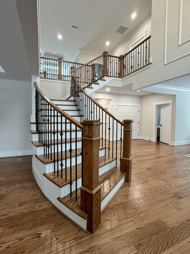 Ejemplo de escalera curva clásica renovada de tamaño medio con escalones de madera, contrahuellas de madera y barandilla de varios materiales