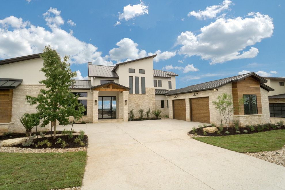 Photo of a large contemporary two-storey beige house exterior in Austin with stone veneer and a metal roof.