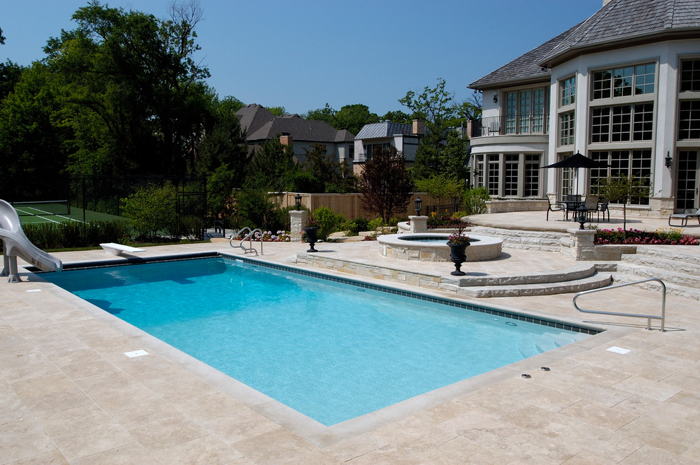 Design ideas for a mid-sized traditional backyard rectangular lap pool in Chicago with a hot tub and natural stone pavers.