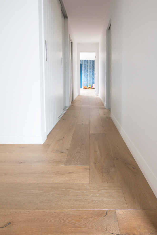 This is an example of a mid-sized eclectic hallway in Auckland with beige walls, light hardwood floors and beige floor.