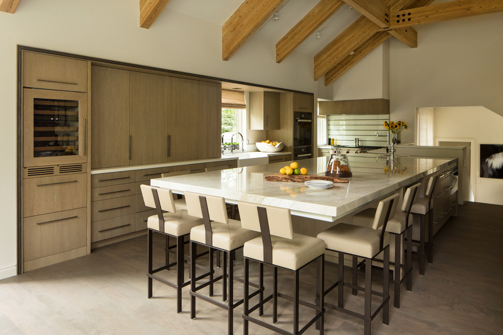Mountain style medium tone wood floor kitchen photo with a farmhouse sink, flat-panel cabinets, medium tone wood cabinets, paneled appliances, an island, white countertops, quartzite countertops, multicolored backsplash and glass sheet backsplash