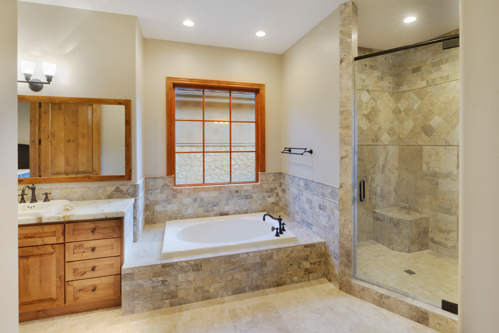 This is an example of a large master bathroom in Other with raised-panel cabinets, light wood cabinets, a drop-in tub, a corner shower, beige tile, travertine, beige walls, limestone floors, a drop-in sink, engineered quartz benchtops, beige floor and a hinged shower door.