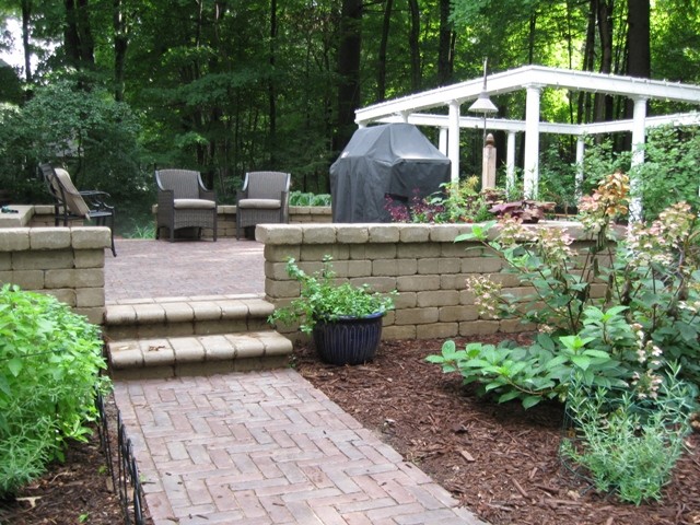 This is an example of a mid-sized traditional partial sun backyard brick retaining wall landscape in Other for spring.