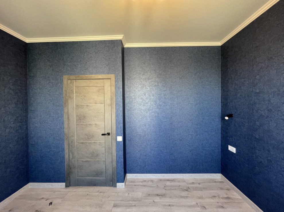 Inspiration pour une chambre parentale design de taille moyenne avec un mur bleu, sol en stratifié, un sol beige et du papier peint.