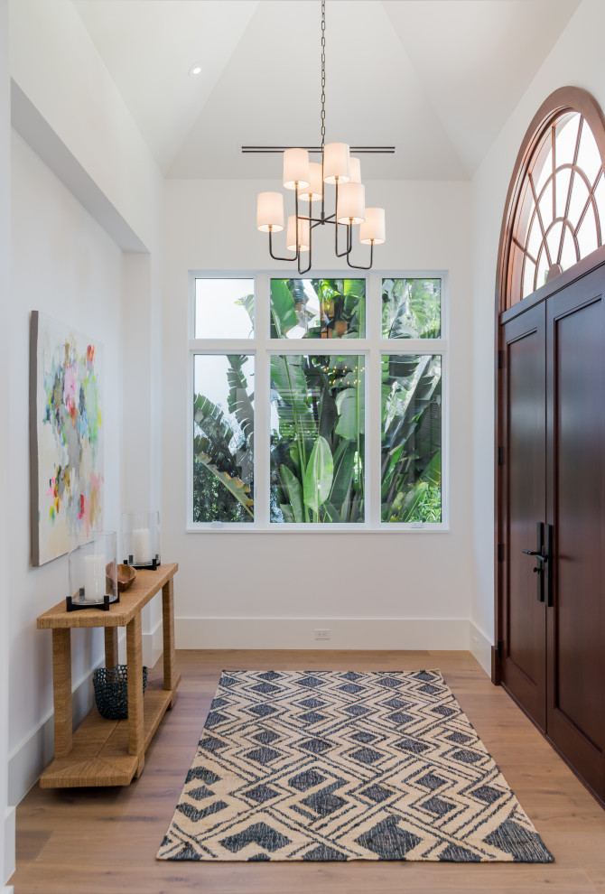This is an example of a large beach style entry hall in Miami with white walls, medium hardwood floors, a double front door, a medium wood front door and beige floor.