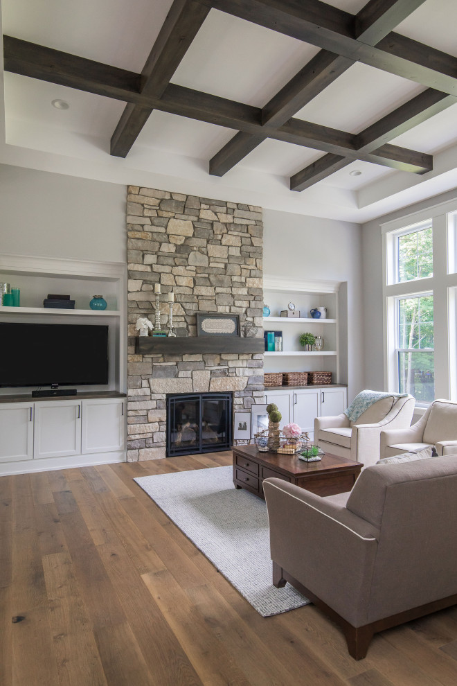 Design ideas for an arts and crafts open concept family room in Grand Rapids with grey walls, medium hardwood floors, a standard fireplace, a built-in media wall, brown floor and exposed beam.