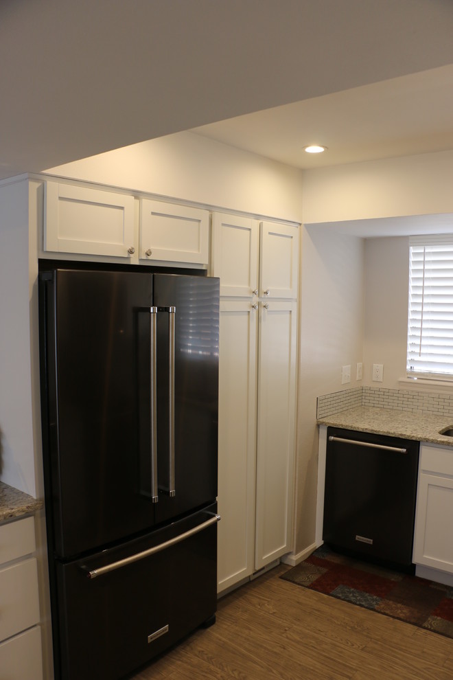 Small transitional u-shaped vinyl floor and brown floor eat-in kitchen photo in Denver with an undermount sink, recessed-panel cabinets, white cabinets, granite countertops, gray backsplash, ceramic backsplash, black appliances, no island and white countertops