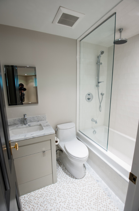 Inspiration for a mid-sized contemporary 3/4 bathroom in Toronto with flat-panel cabinets, beige cabinets, a corner tub, a shower/bathtub combo, a one-piece toilet, white tile, beige walls, pebble tile floors, an undermount sink and marble benchtops.