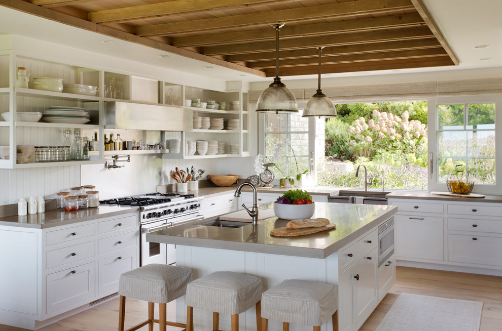 Inspiration for a country l-shaped kitchen in Boston with a farmhouse sink, shaker cabinets, light wood cabinets, white splashback, stainless steel appliances, light hardwood floors and with island.