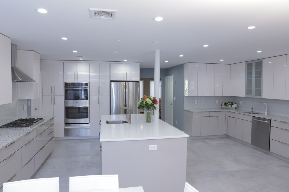 Design ideas for a large modern u-shaped separate kitchen in New York with a drop-in sink, flat-panel cabinets, white cabinets, recycled glass benchtops, blue splashback, glass sheet splashback, stainless steel appliances, concrete floors and with island.