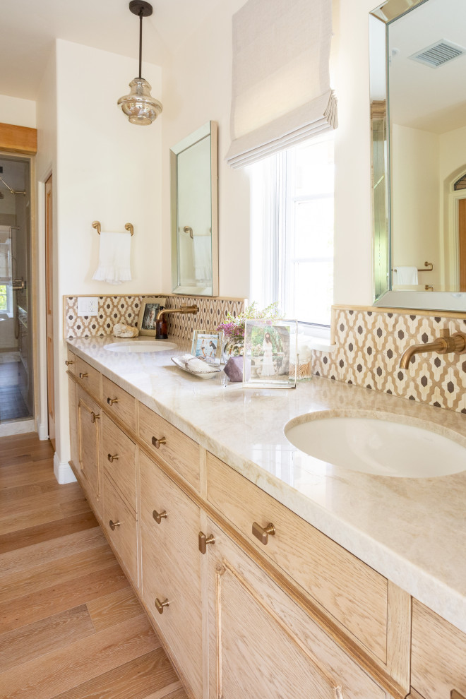 Photo of a large master bathroom in Santa Barbara with light wood cabinets, a freestanding tub, an open shower, a two-piece toilet, white tile, porcelain tile, white walls, light hardwood floors, an undermount sink, quartzite benchtops, beige floor, a hinged shower door, beige benchtops, a shower seat, a double vanity and a built-in vanity.