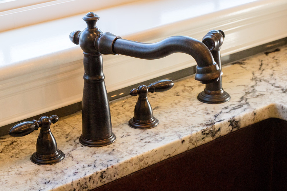 Example of a transitional l-shaped dark wood floor kitchen design in Providence with a farmhouse sink, raised-panel cabinets, granite countertops, gray backsplash, glass tile backsplash, paneled appliances and an island