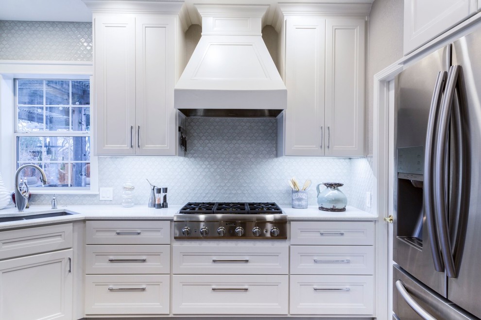 Example of a mid-sized transitional dark wood floor kitchen design in Dallas with a double-bowl sink, recessed-panel cabinets, white cabinets, quartzite countertops, blue backsplash, glass tile backsplash, stainless steel appliances and an island
