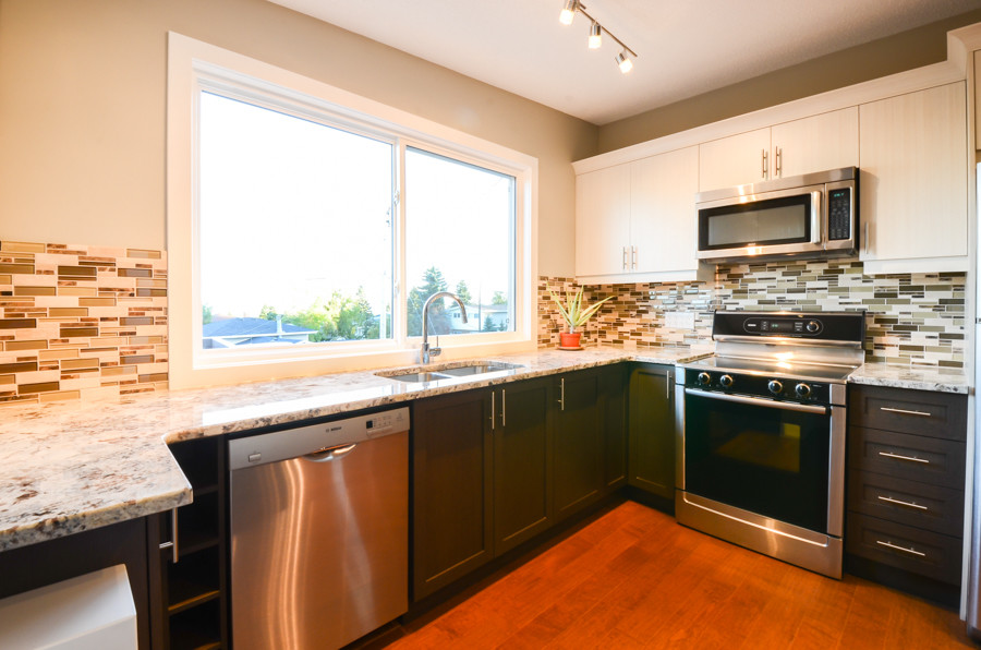 Example of a small transitional l-shaped medium tone wood floor open concept kitchen design in Calgary with an undermount sink, shaker cabinets, dark wood cabinets, marble countertops, multicolored backsplash, matchstick tile backsplash, stainless steel appliances and an island