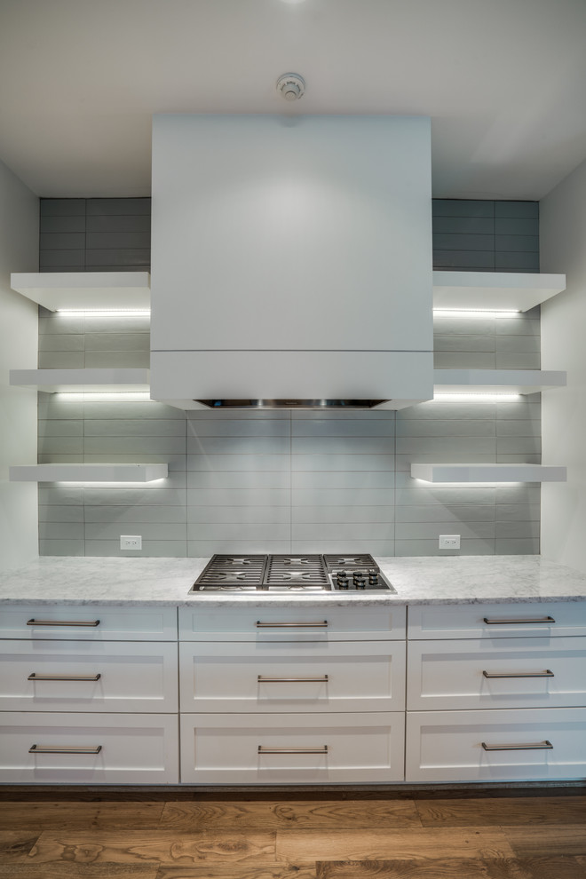 Example of a large transitional single-wall light wood floor kitchen design in Dallas with an undermount sink, shaker cabinets, white cabinets, marble countertops, white backsplash, an island and stainless steel appliances