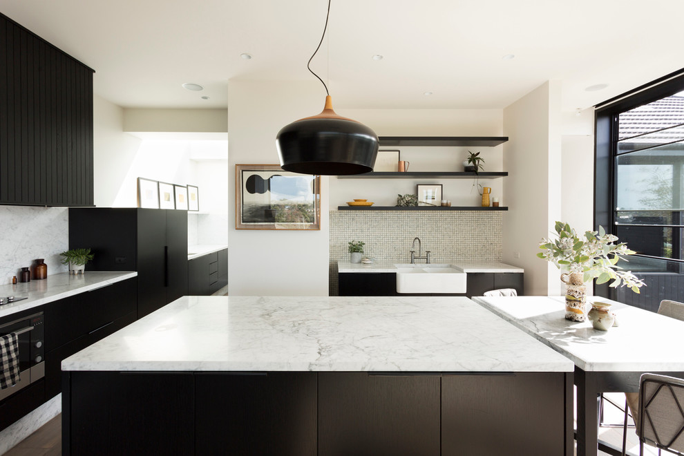 Photo of a large scandinavian l-shaped eat-in kitchen in Melbourne with a farmhouse sink, black cabinets, marble benchtops, multi-coloured splashback, mosaic tile splashback, stainless steel appliances, medium hardwood floors and with island.