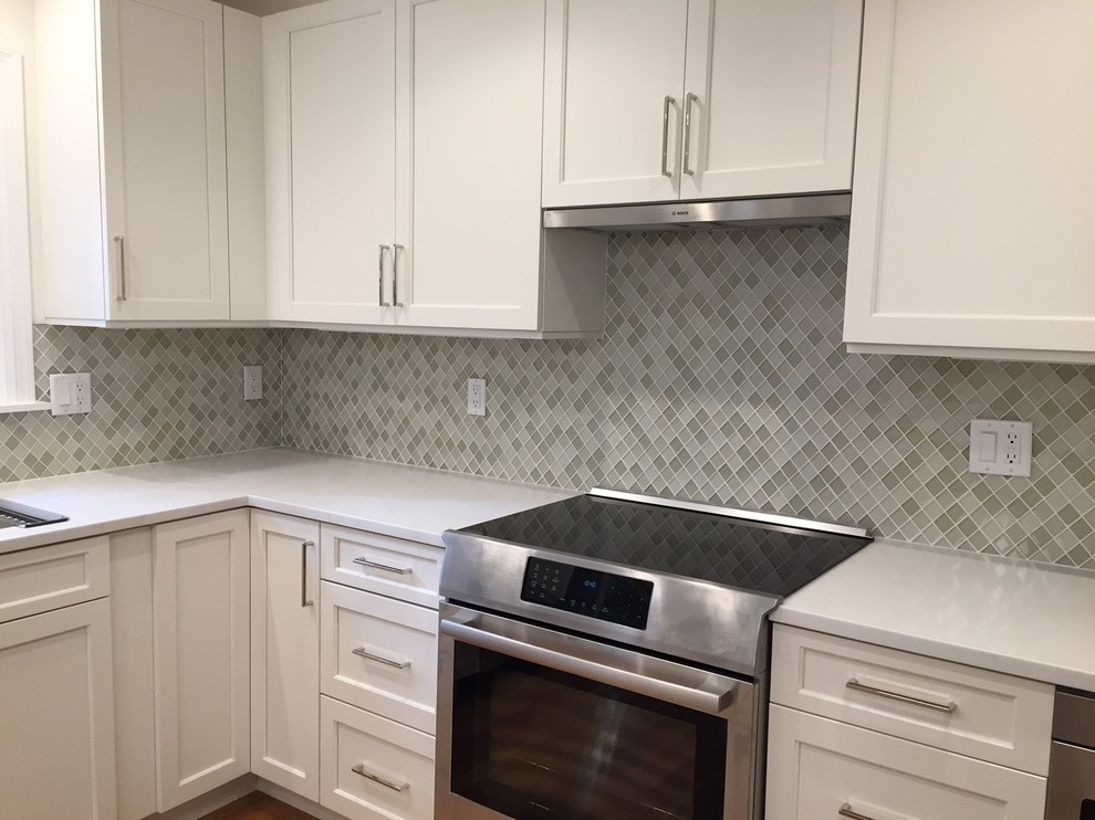 Eat-in kitchen - transitional u-shaped medium tone wood floor and brown floor eat-in kitchen idea in New York with a single-bowl sink, shaker cabinets, white cabinets, quartz countertops, multicolored backsplash, glass sheet backsplash, stainless steel appliances, an island and white countertops