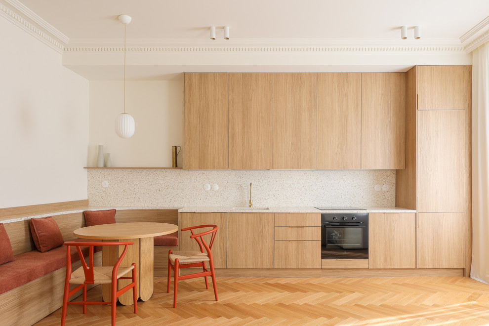 Mid-sized transitional single-wall eat-in kitchen in Nice with an integrated sink, beaded inset cabinets, light wood cabinets, terrazzo benchtops, multi-coloured splashback, marble splashback, panelled appliances, light hardwood floors, no island, brown floor and multi-coloured benchtop.