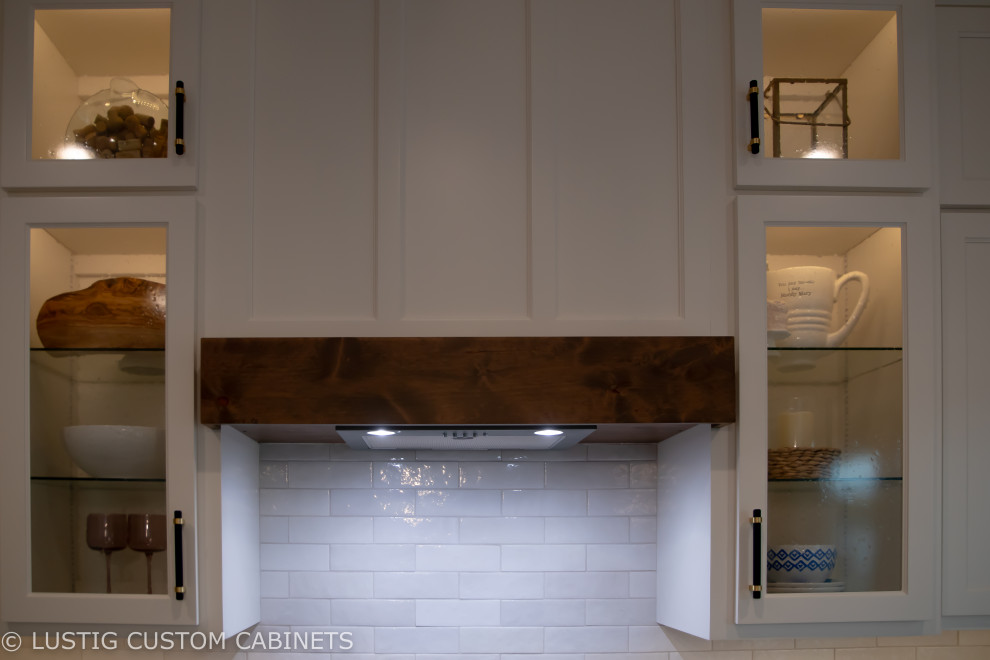 Large transitional l-shaped laminate floor and brown floor open concept kitchen photo with an undermount sink, flat-panel cabinets, white cabinets, quartz countertops, white backsplash, ceramic backsplash, stainless steel appliances, an island and white countertops