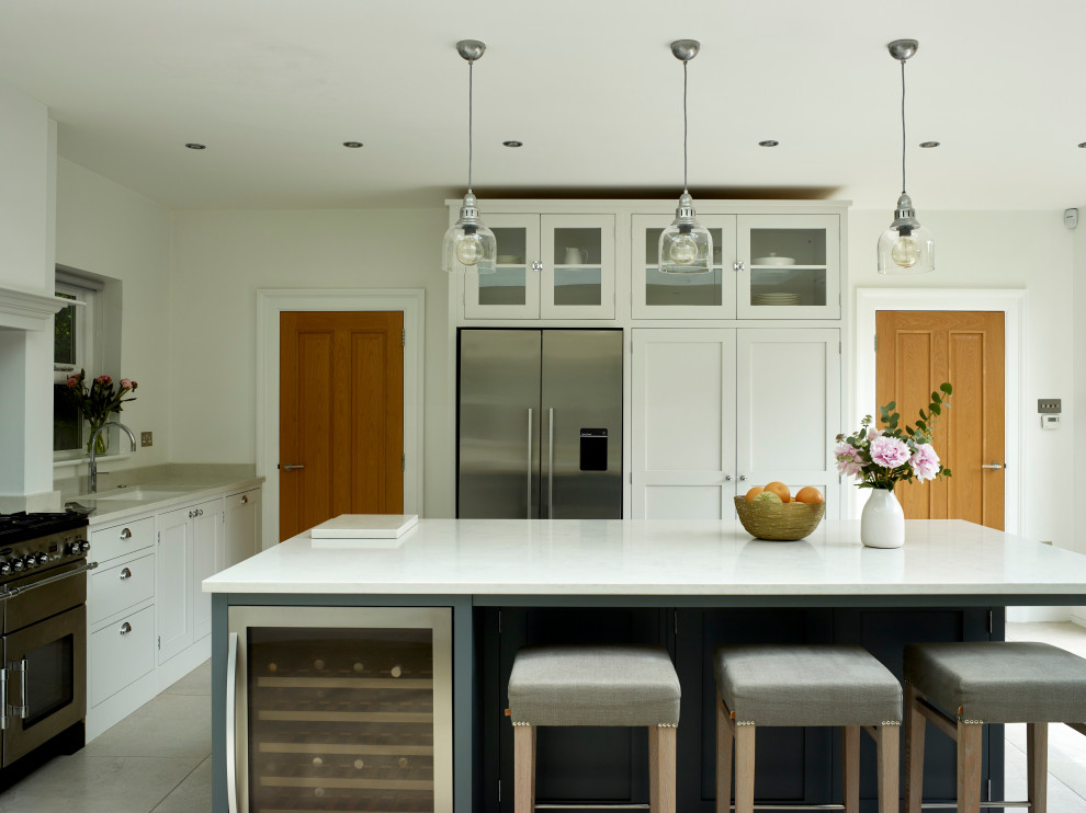 Inspiration for a large contemporary l-shaped open plan kitchen in Hertfordshire with a drop-in sink, shaker cabinets, grey cabinets, quartzite benchtops, white splashback, stone slab splashback, stainless steel appliances, porcelain floors, with island, white floor and white benchtop.