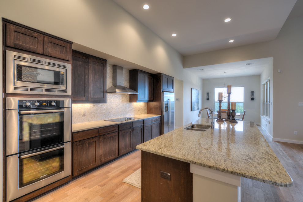 Example of a transitional light wood floor eat-in kitchen design in Austin with granite countertops, white backsplash, mosaic tile backsplash, stainless steel appliances and an island