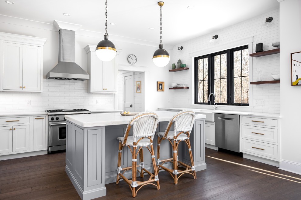 Kitchen - mid-sized transitional l-shaped dark wood floor and brown floor kitchen idea in Providence with a farmhouse sink, beaded inset cabinets, white cabinets, white backsplash, stainless steel appliances, an island and white countertops
