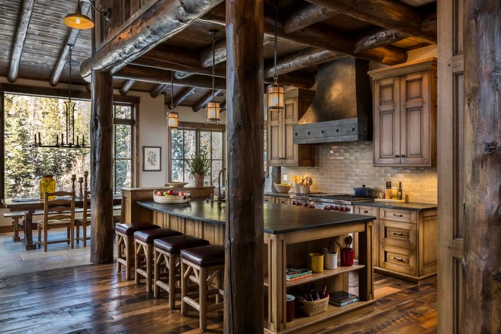 Large mountain style galley dark wood floor eat-in kitchen photo in Denver with raised-panel cabinets, medium tone wood cabinets, an island, soapstone countertops, beige backsplash, stone tile backsplash, stainless steel appliances and a farmhouse sink