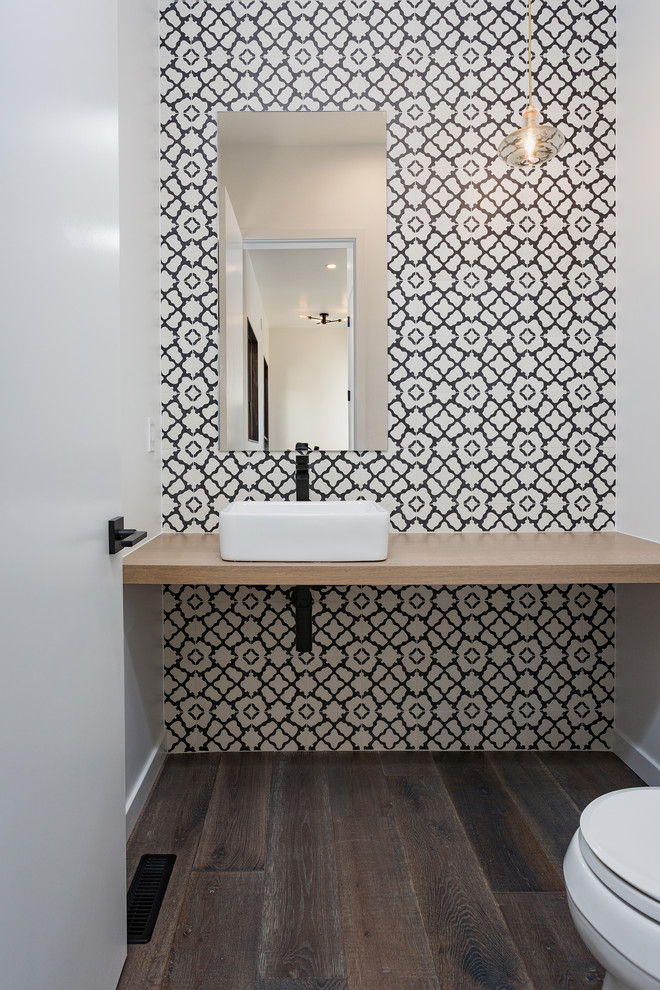 This is an example of a contemporary powder room in Albuquerque with black and white tile, cement tile, white walls, medium hardwood floors, a vessel sink, wood benchtops and grey floor.