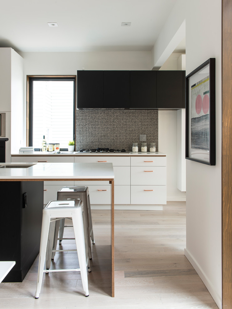 Design ideas for a contemporary galley kitchen in Toronto with an undermount sink, flat-panel cabinets, black cabinets, grey splashback, light hardwood floors, beige floor and white benchtop.