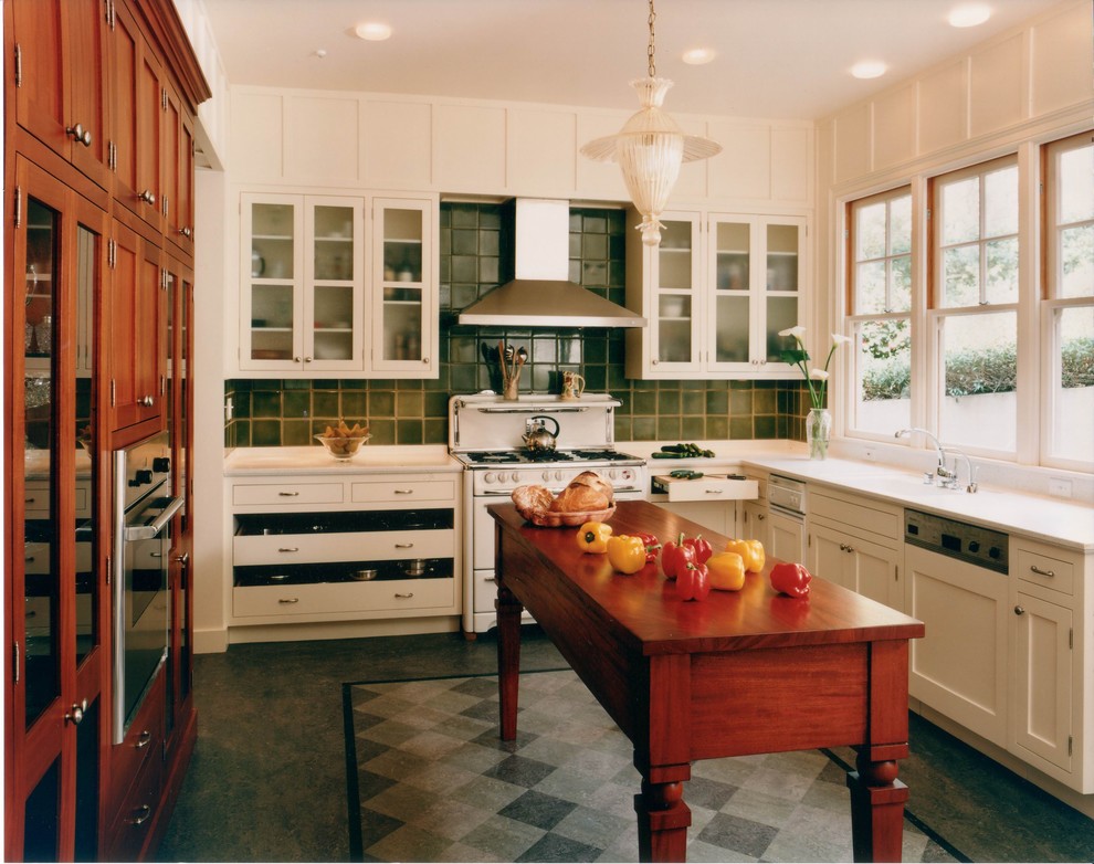 Inspiration for a traditional l-shaped kitchen in San Francisco with glass-front cabinets, white cabinets, green splashback and white appliances.