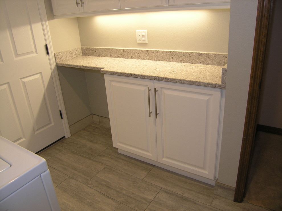 Inspiration for a mid-sized traditional u-shaped dedicated laundry room in Tampa with raised-panel cabinets, white cabinets, granite benchtops, grey walls, porcelain floors, a side-by-side washer and dryer and grey floor.