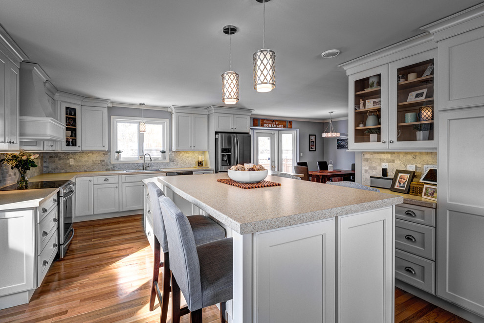 This is an example of a traditional l-shaped eat-in kitchen in Other with a drop-in sink, beaded inset cabinets, white cabinets, beige splashback, medium hardwood floors and with island.