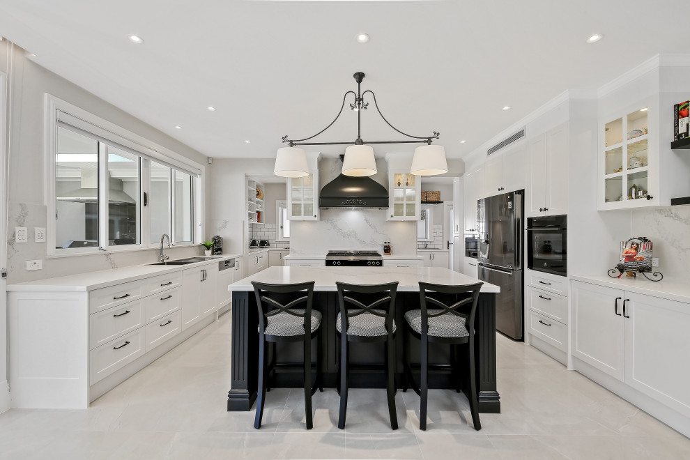 Inspiration for a large transitional u-shaped eat-in kitchen in Sydney with a double-bowl sink, beaded inset cabinets, quartz benchtops, white splashback, subway tile splashback, stainless steel appliances, ceramic floors, with island, white floor and white benchtop.