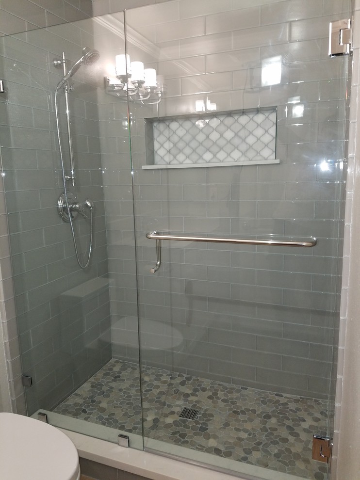 This is an example of a traditional 3/4 bathroom in Los Angeles with an alcove shower, gray tile, glass tile and a hinged shower door.