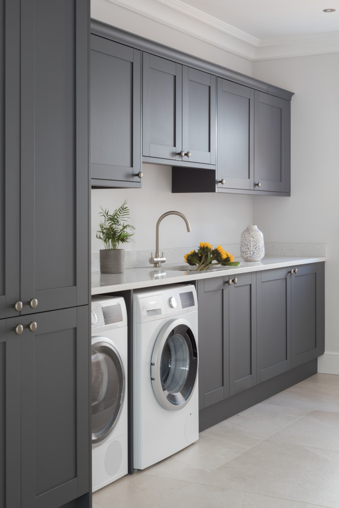 Mid-sized transitional single-wall laundry room in Other with shaker cabinets, grey cabinets, grey walls, porcelain floors, a side-by-side washer and dryer, beige floor and white benchtop.