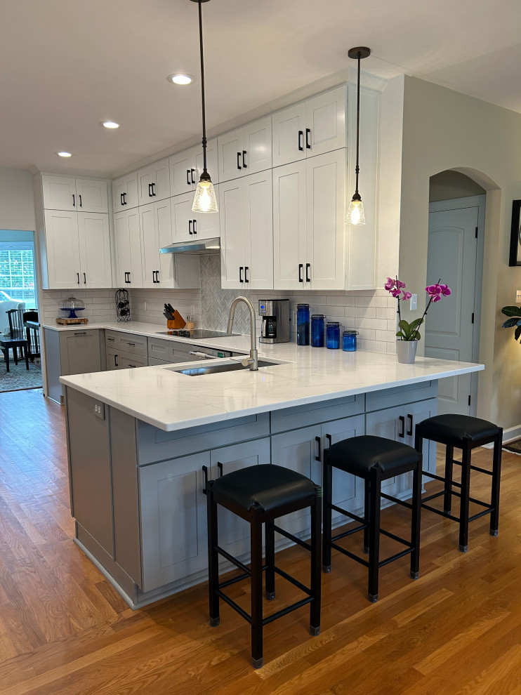 Large classic u-shaped kitchen/diner in Raleigh with shaker cabinets, engineered stone countertops and white splashback.