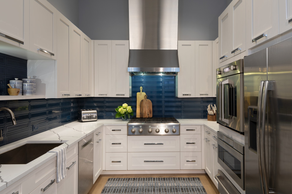 Inspiration for a mid-sized beach style u-shaped kitchen pantry in Other with a triple-bowl sink, recessed-panel cabinets, white cabinets, blue splashback, ceramic splashback, stainless steel appliances, medium hardwood floors and multiple islands.
