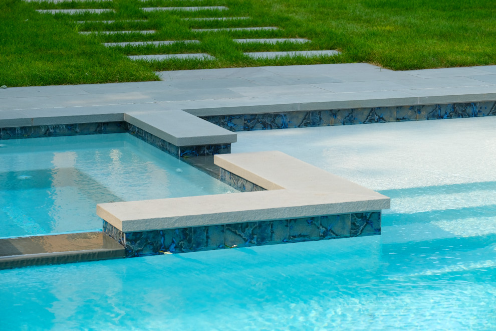 Modelo de piscina alargada clásica de tamaño medio rectangular en patio trasero con privacidad y adoquines de piedra natural