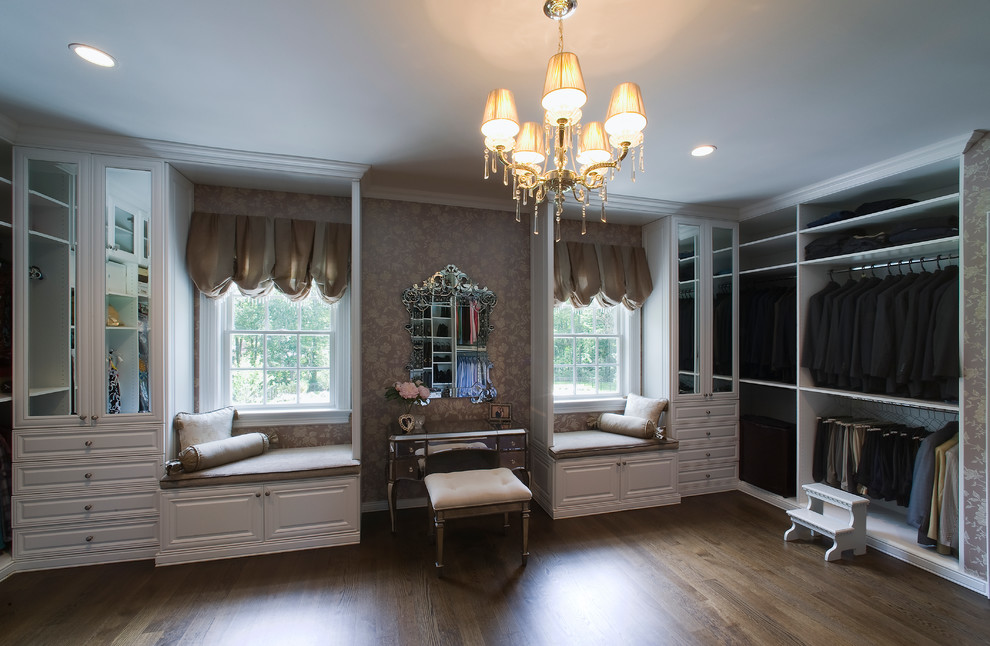 Expansive traditional women's walk-in wardrobe in New York with raised-panel cabinets, white cabinets and dark hardwood floors.