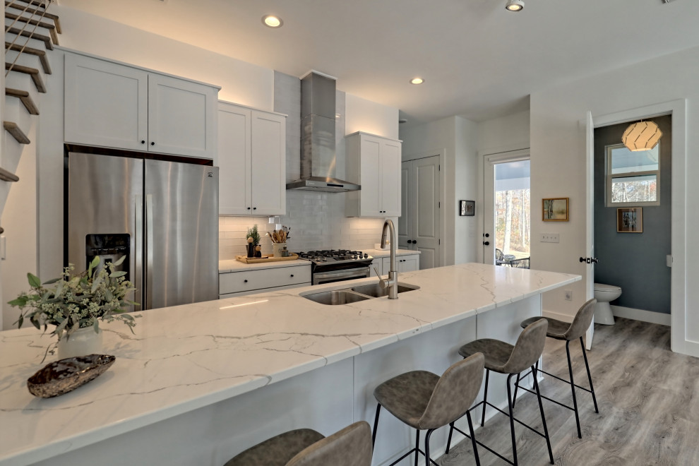 Photo of a small country galley open plan kitchen in Atlanta with an undermount sink, shaker cabinets, white cabinets, quartz benchtops, glass tile splashback, stainless steel appliances, a peninsula and white benchtop.
