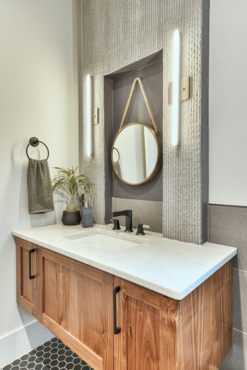Photo of a mid-sized transitional powder room in Austin with shaker cabinets, medium wood cabinets, gray tile, white walls, an undermount sink, grey floor, ceramic floors and white benchtops.