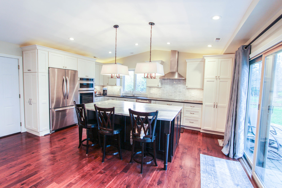 Eat-in kitchen - mid-sized transitional l-shaped medium tone wood floor eat-in kitchen idea in Cincinnati with an undermount sink, recessed-panel cabinets, white cabinets, quartzite countertops, white backsplash, subway tile backsplash, stainless steel appliances and an island