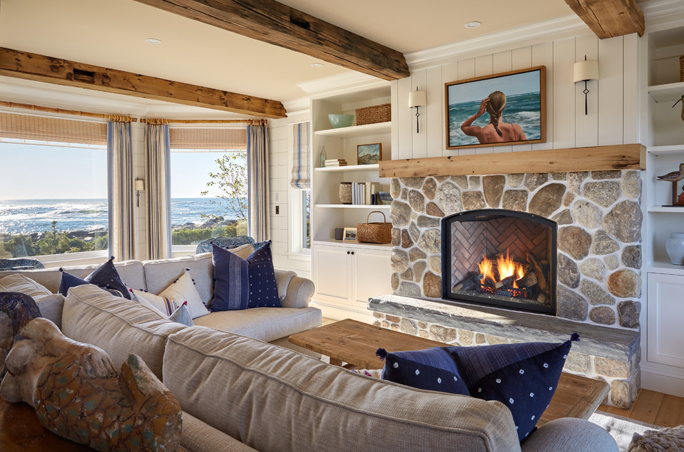 Beach style living room in Portland Maine with a library, white walls, a standard fireplace, a stone fireplace surround and no tv.