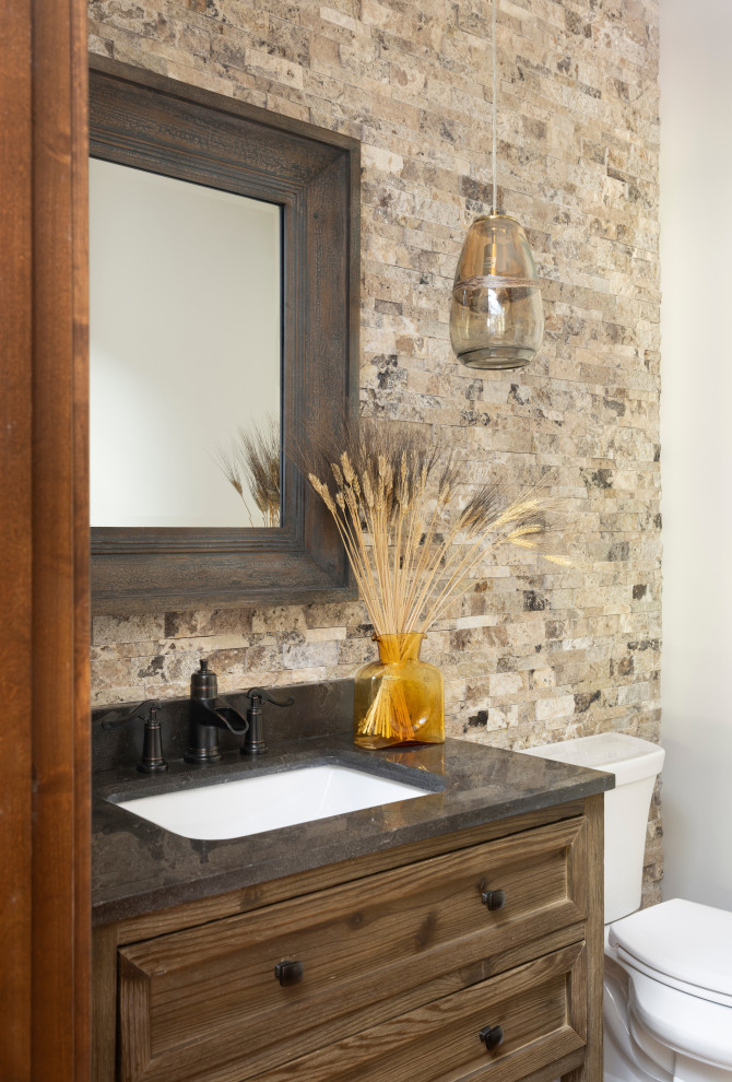 Inspiration for a farmhouse ceramic tile powder room remodel in Denver with shaker cabinets, brown cabinets, a two-piece toilet, an undermount sink, quartzite countertops, gray countertops and a freestanding vanity