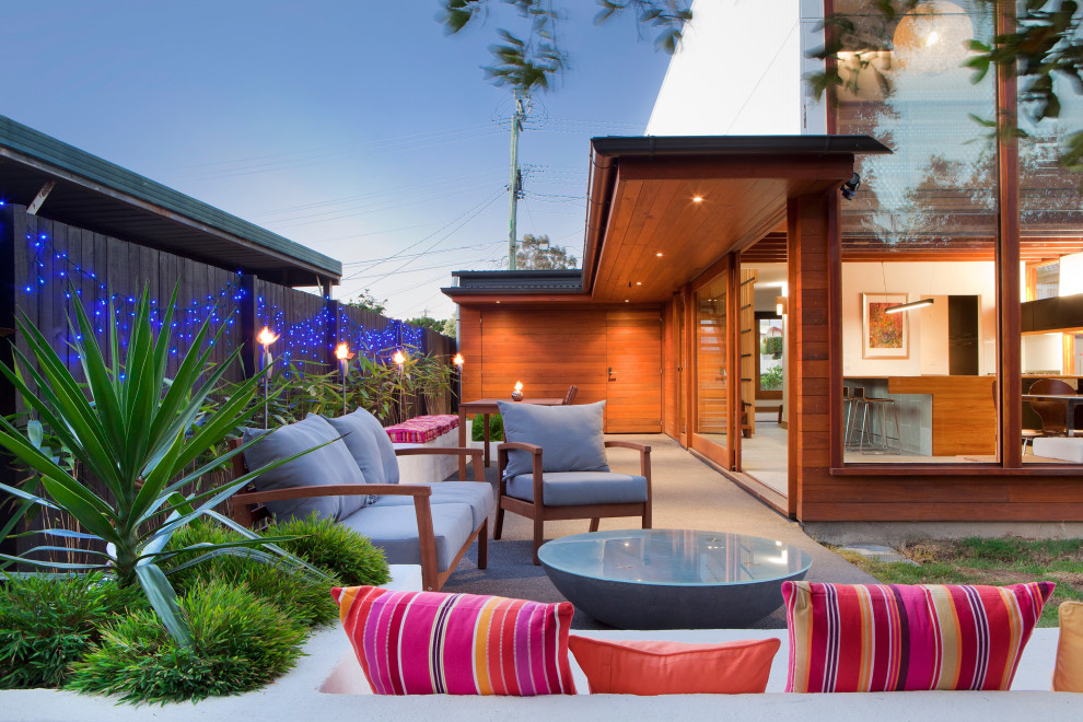 Photo of a mid-sized contemporary backyard patio in Brisbane with a fire feature, gravel and an awning.